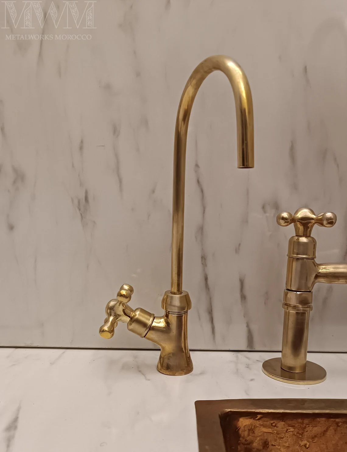 Aged brass gooseneck spout and drinking water faucet over a copper sink