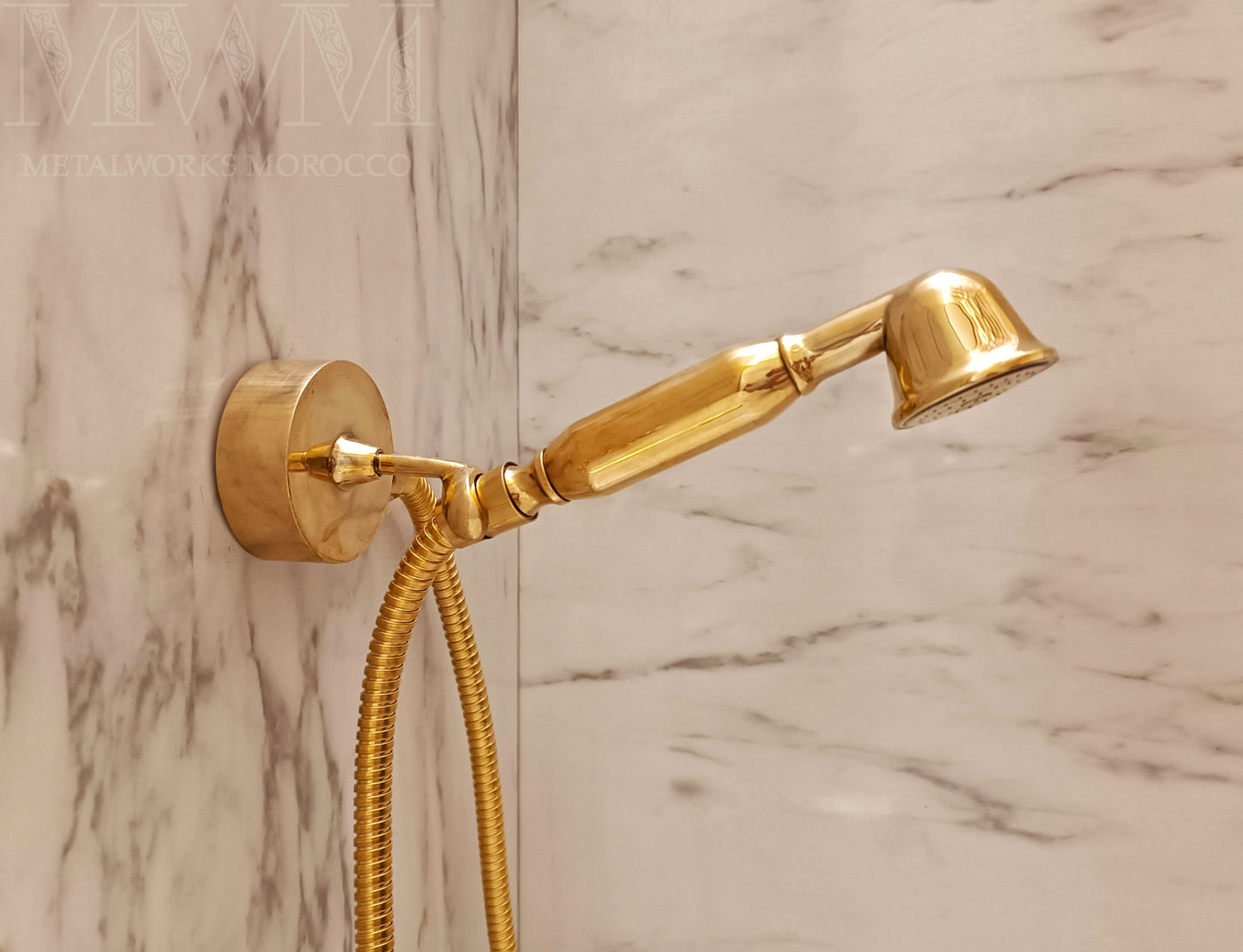 Brass hand shower mounted in marble bathroom with swivel wall cradle