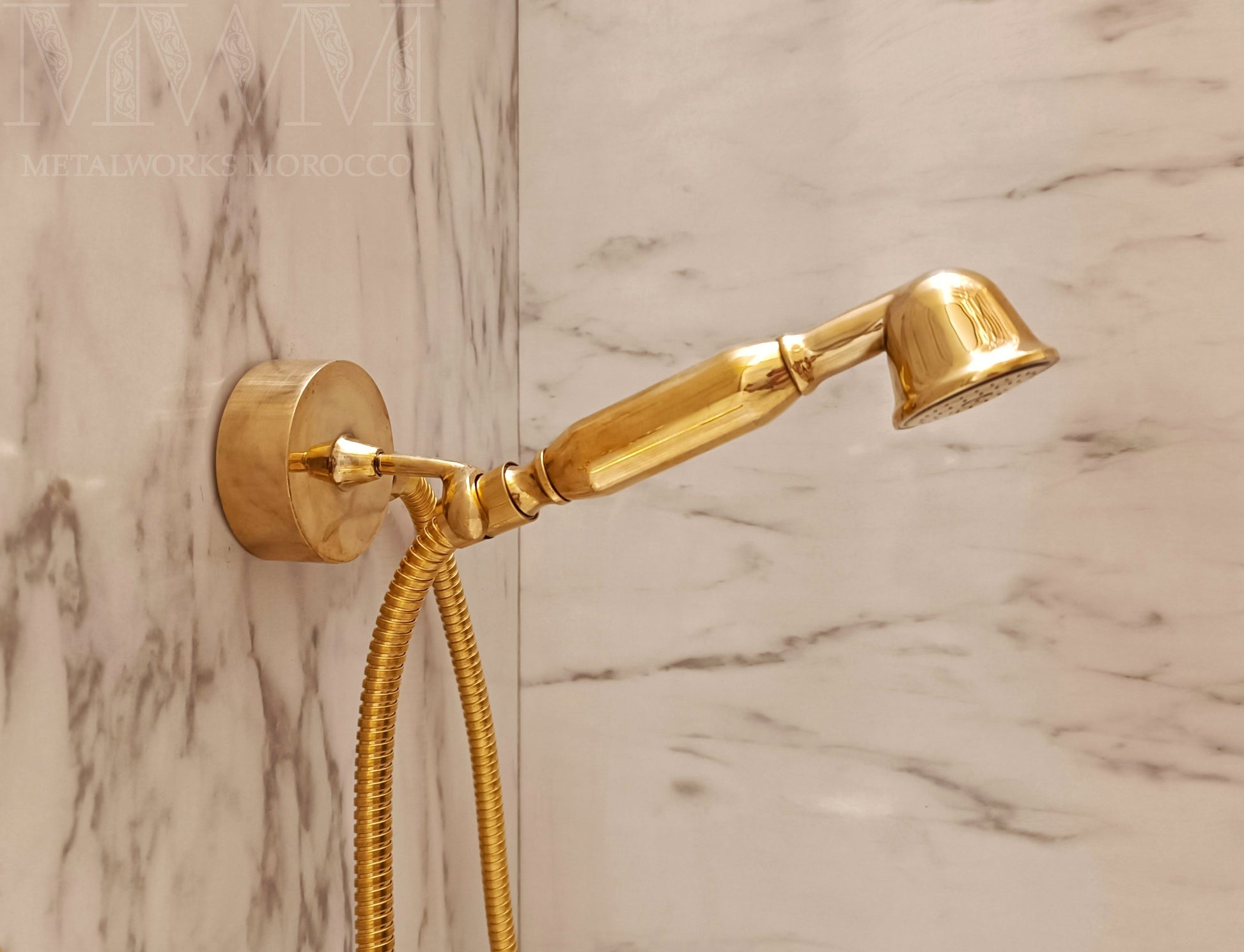 Brass hand shower mounted in marble bathroom with swivel wall cradle