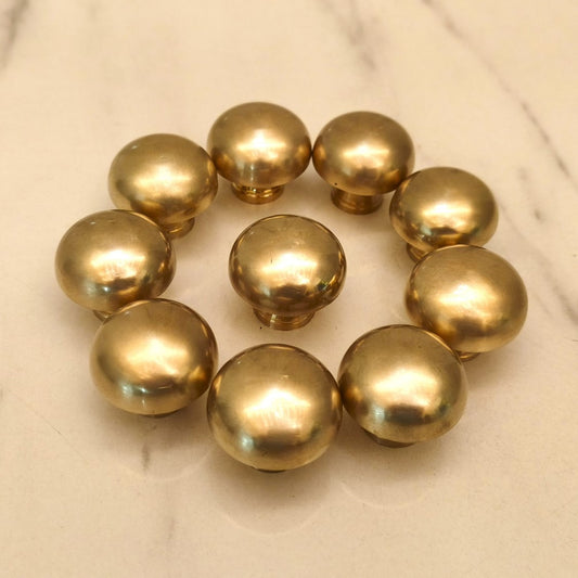 Set of handmade burnished brass cabinet knobs arranged in a circle on white marble